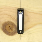 Close-up picture of one of the doorbell buttons in the experiment.
		This button looks like a piano key, the casing is metallic and the functional component
		of the button is made of plastic.