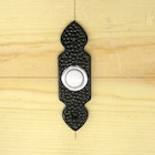 Close-up picture of one of the doorbell buttons in the experiment.
		This button has a small white round pressable part, which is surrounded by a small metal ring.
		The remaining part of the button's casing is made of plastic and has black color.