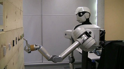 Image of the humanoid robot pressing a doorbell button.